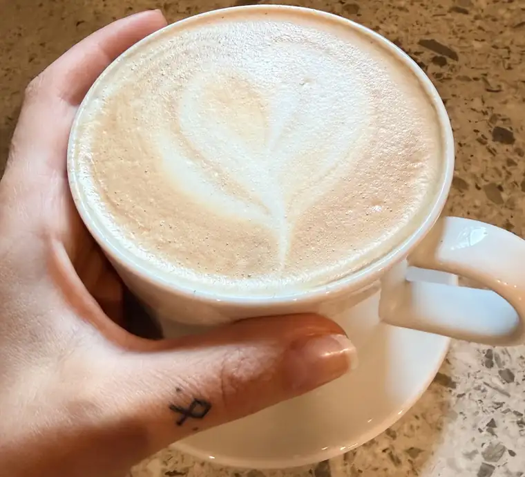 Cappuccino z latte art w dłoni
